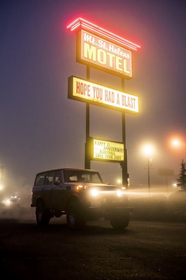 FJ55 Land Cruiser Beside Neon Hotel Sign In Evening