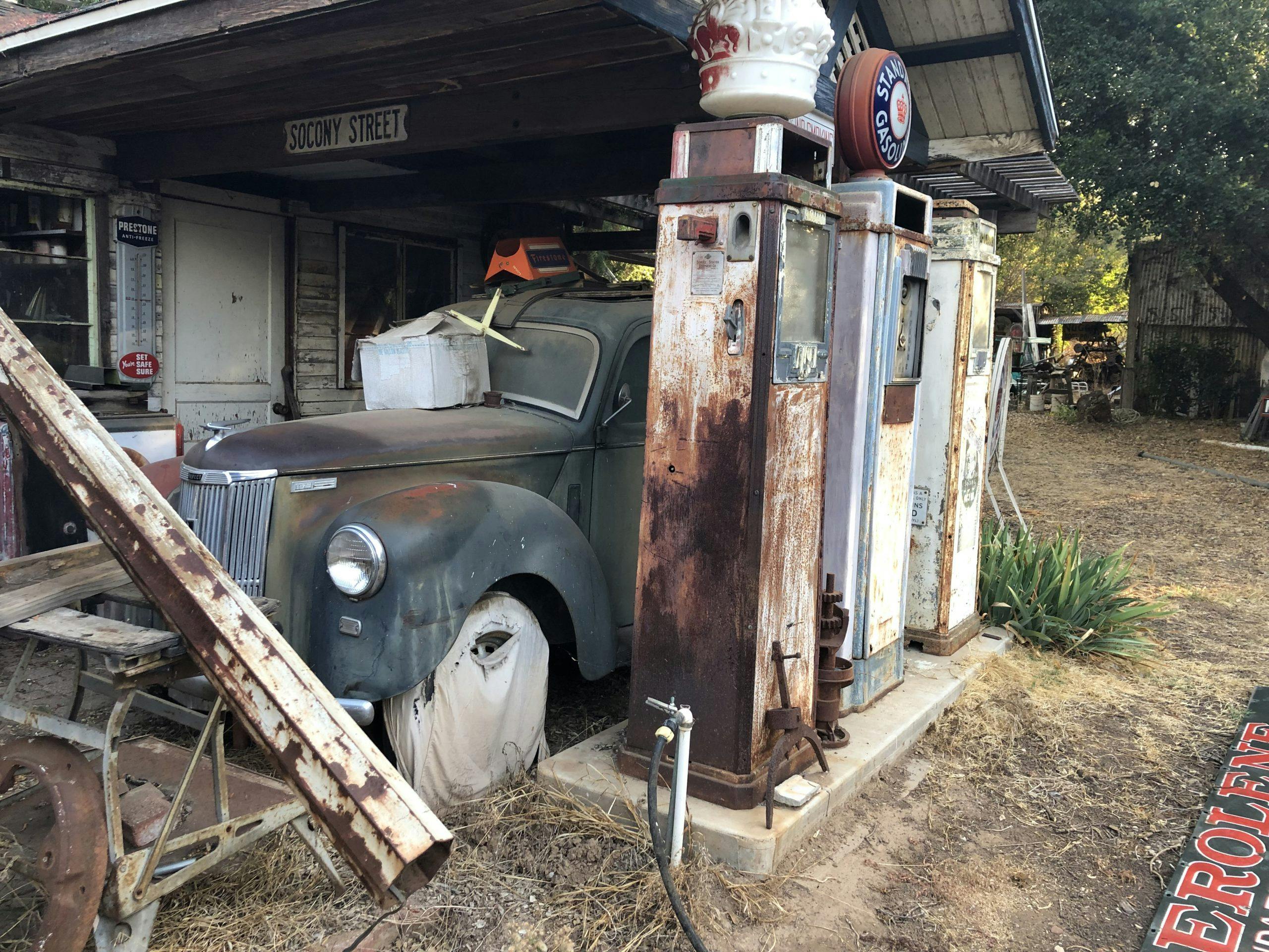 vintage car behind antique gas pumps