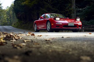 Mazda RX-7 front three-quarter dynamic road action lights up