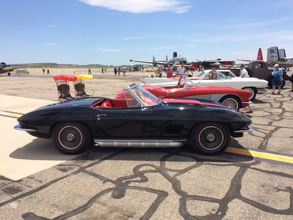 vintage black corvette convertible side profile at airstrip