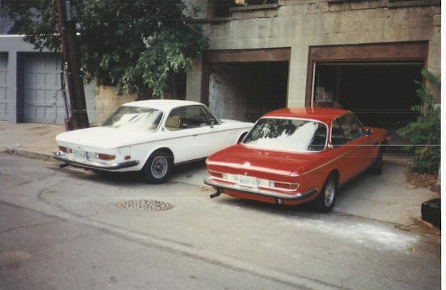 two BMW E9 coupes outside garage stalls