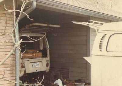 two vintage VW buses outside and under cover