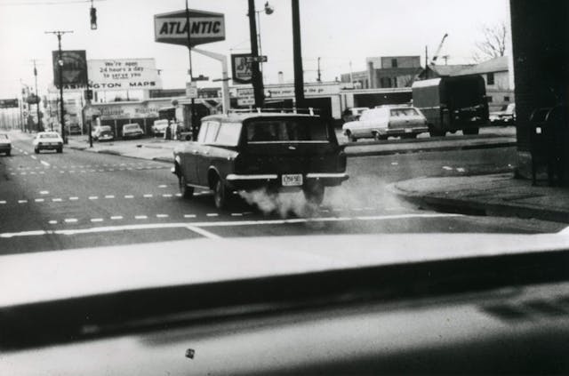 stationwagon gives off exhaust as it drives down the street