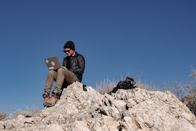 sam smith macbook and camera gear sitting on a rock
