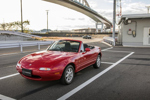 red na miata front three-quarter parked highway overpass