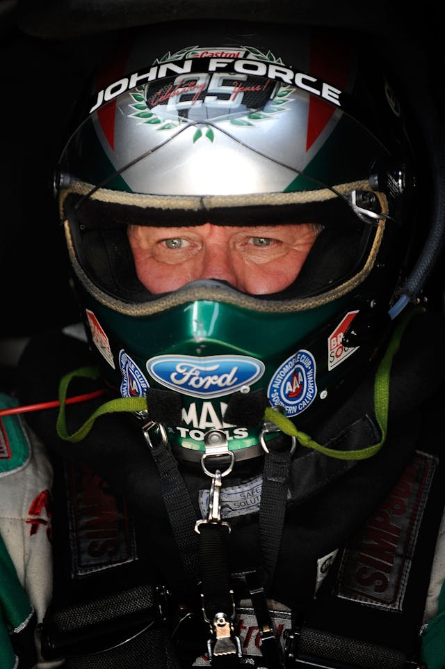 John Force racing in helmet and gear