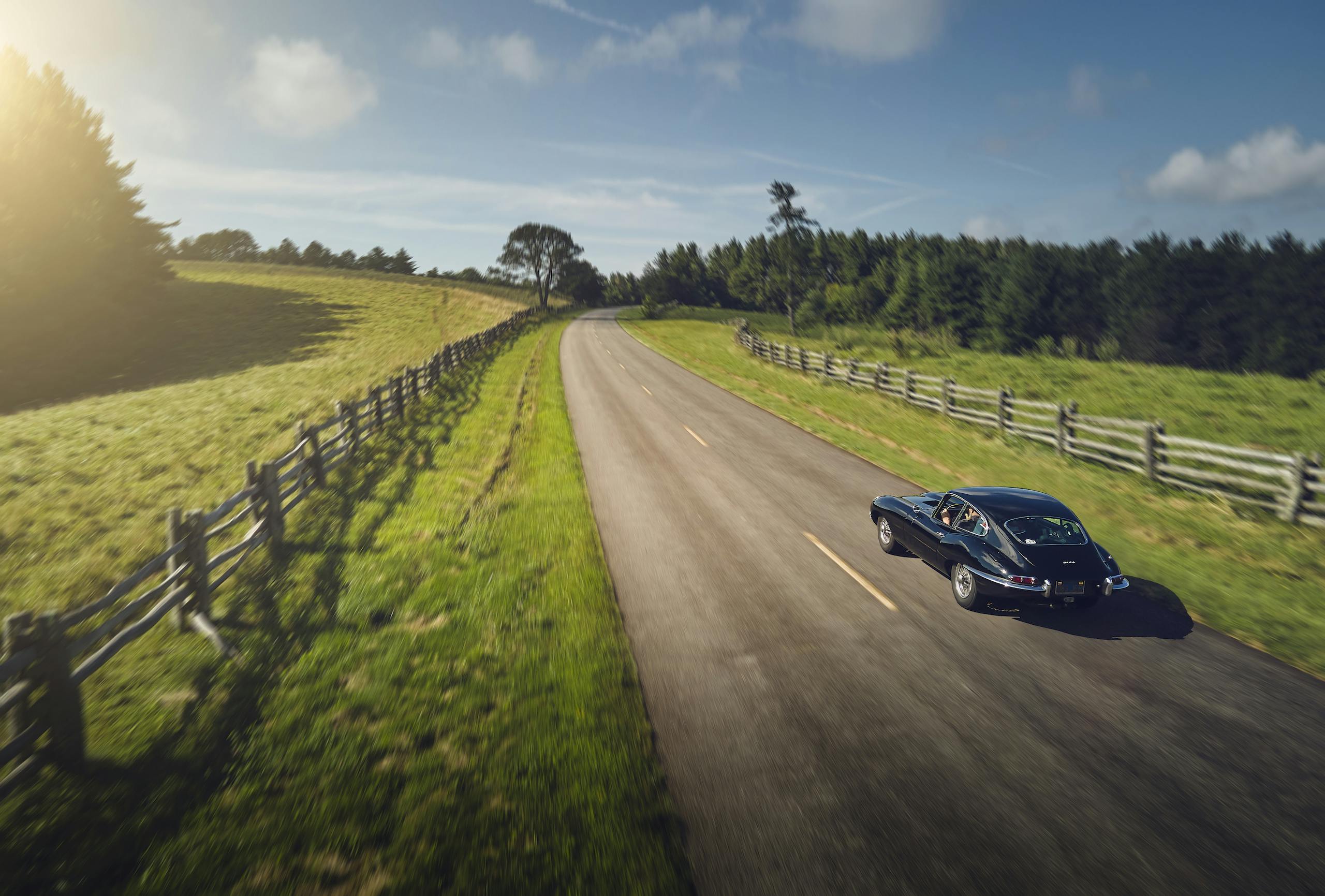 Jaguar E-Type rural road rear three-quarter action