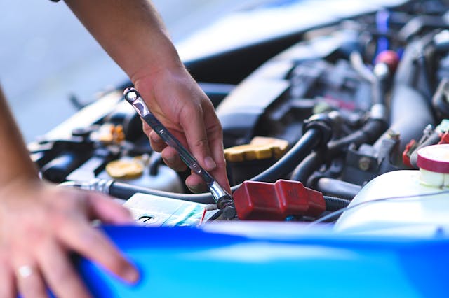 Cropped Hands Of Mechanic maintain car battery