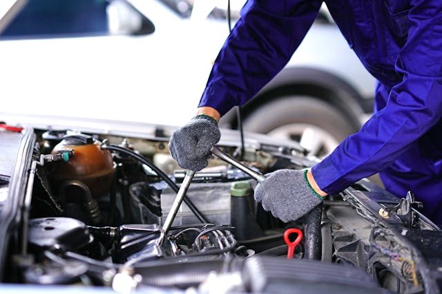 Auto mechanic using repair tools