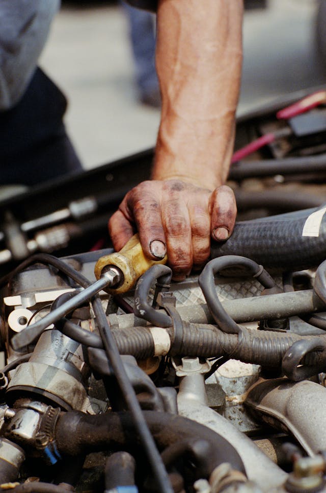 Auto mechanic working on motor closeup vertical