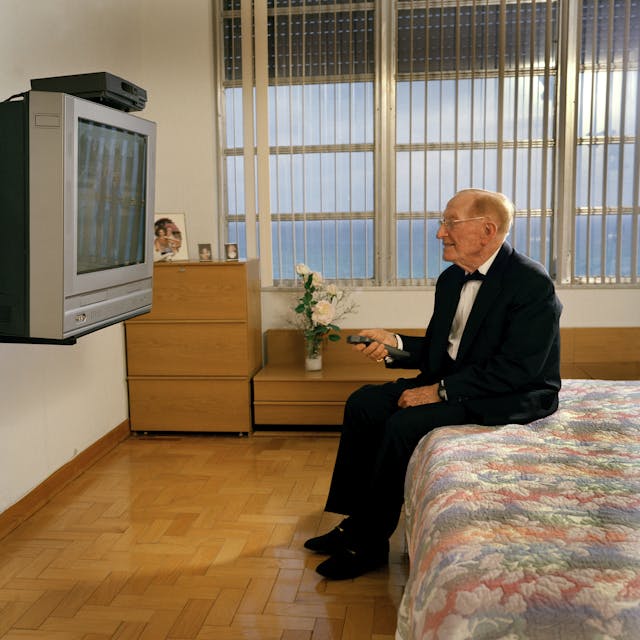 Senior man wearing tuxedo using old tv