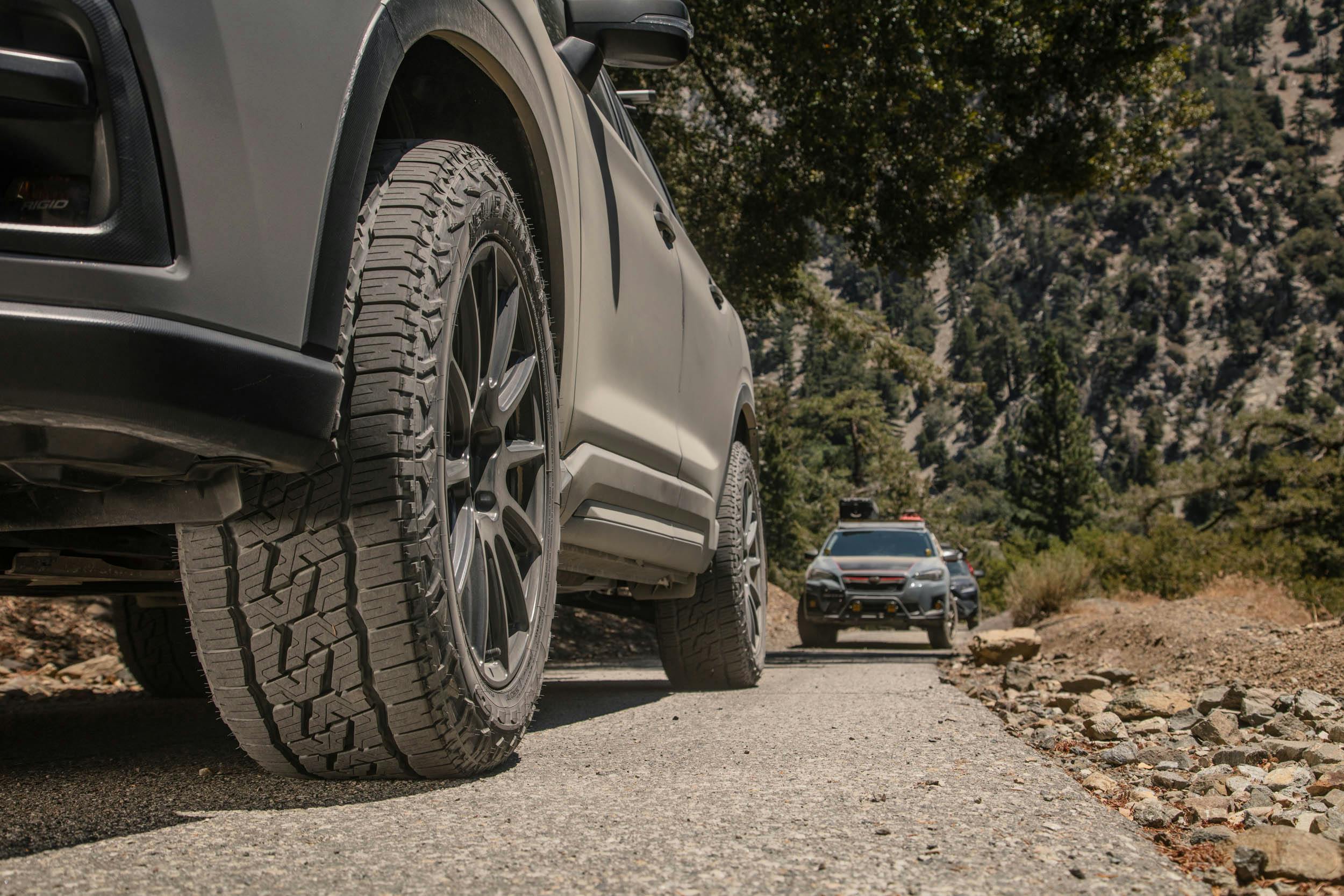 Nitto Tires Nomad Grappler tire closeup two SUVs on road