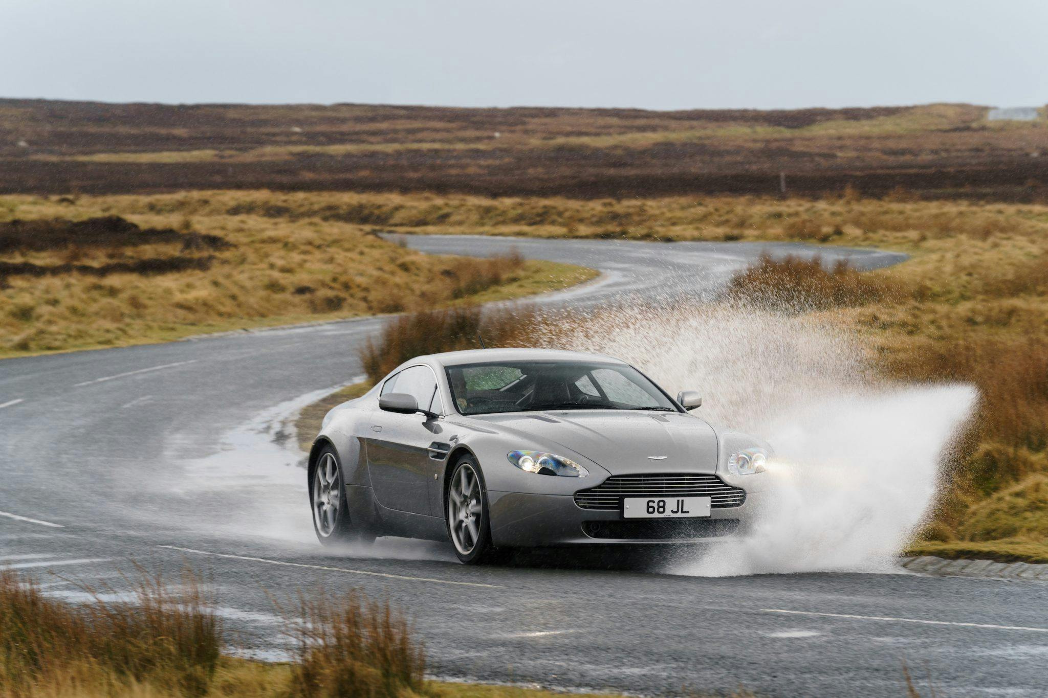 Aston Martin V8 Vantage front three-quarter driving action rainy day