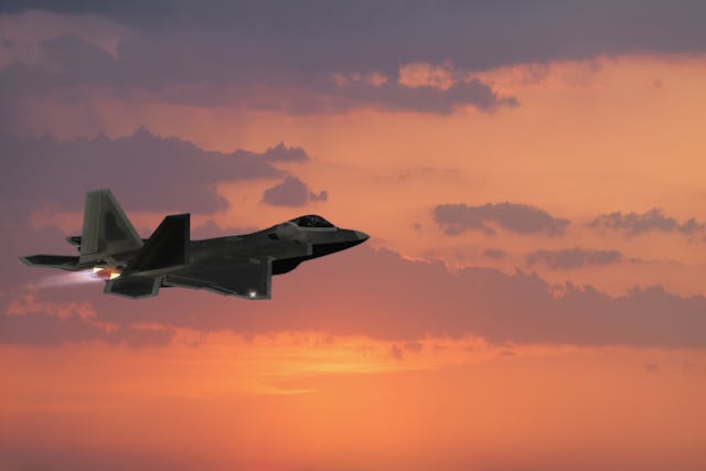 F-22 Fighter Jet flying with afterburner at sunset