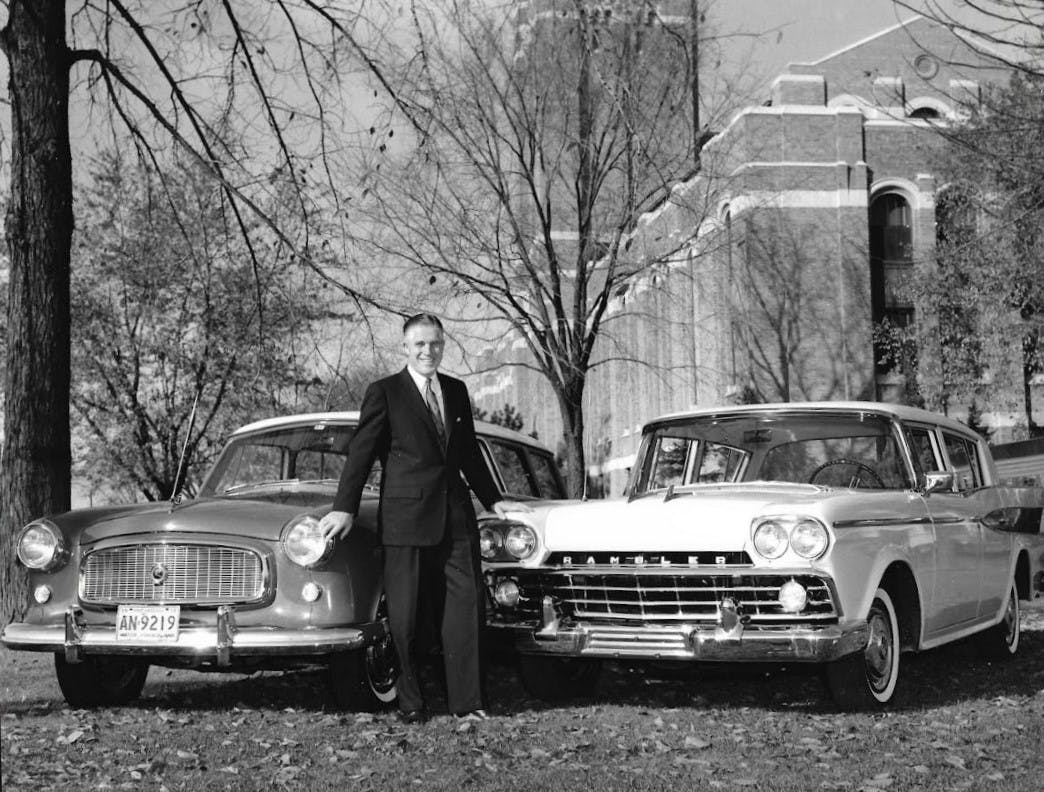 George Romney, chairman and president of American Motors Corporation, poses with a pair of Nash automobiles in 1955.