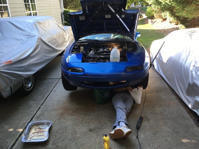 man underneath mazda miata driveway maintenance