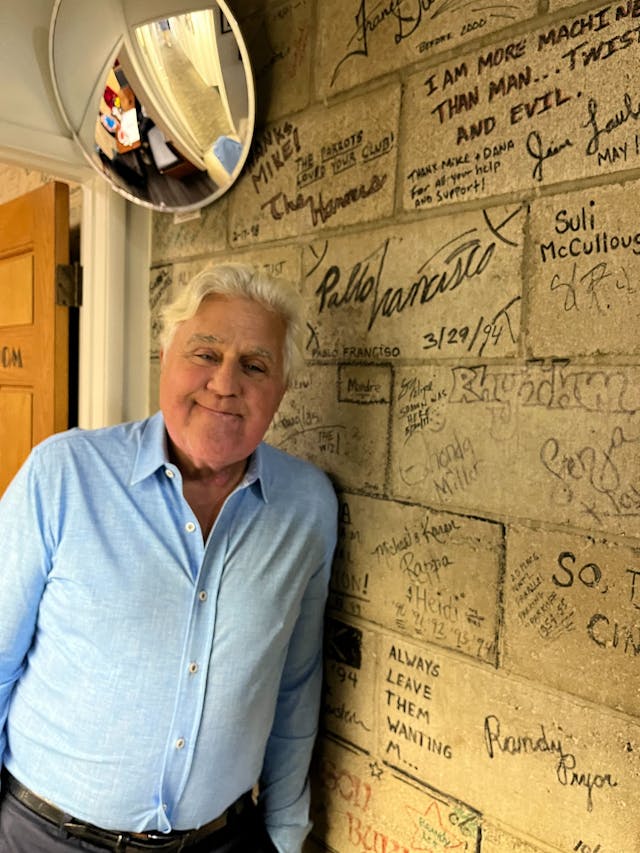 Jay Leno next to signed wall