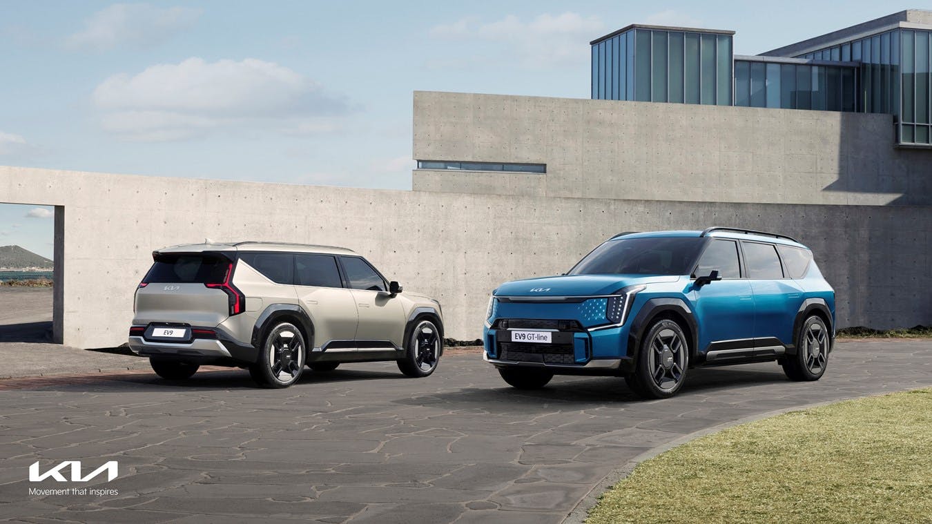 Kia EV9 exterior blue and grey front and rear three quarter by cement house