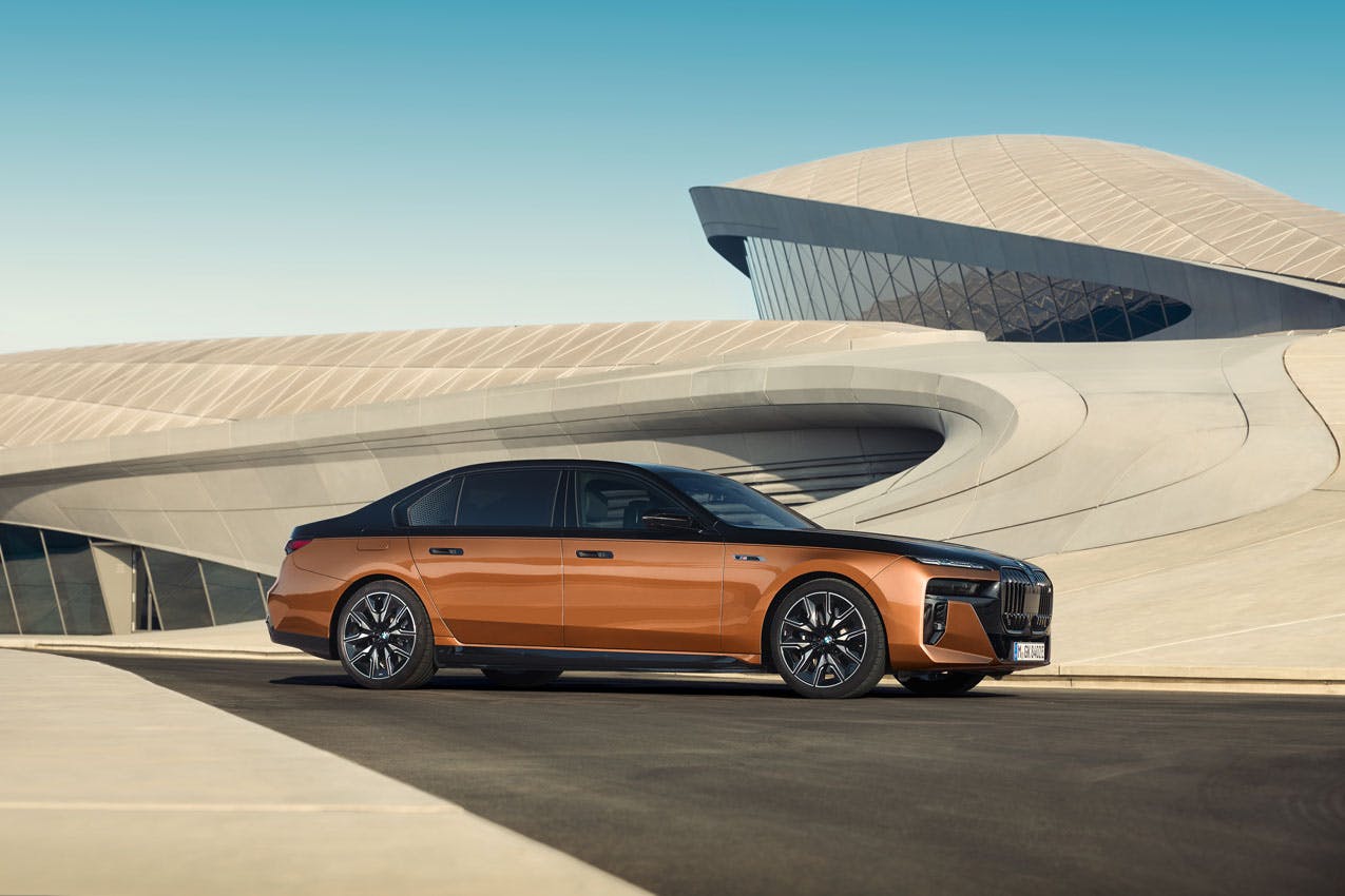 2024 BMW i7 M70 xDrive exterior side profile closer in front of curved building