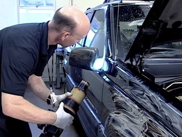 A technician uses a powerful light to examine a Jeep Grand Cherokee.