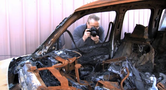 An investigator photographs a burned up truck.