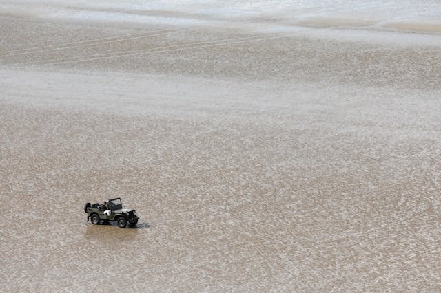 People sit in a jeep on the beach Normandy 2019
