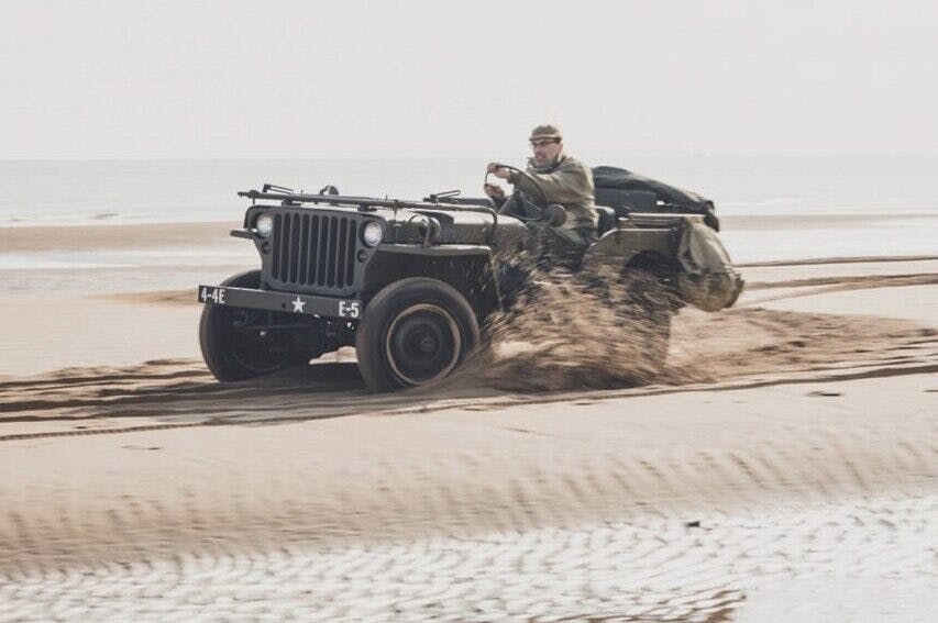 Classic Military Willys Jeep beach driving action vertical