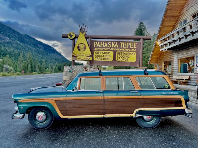 Never Stop Driving Ford Country Squire side profile parked by Pahaska Teepee sign