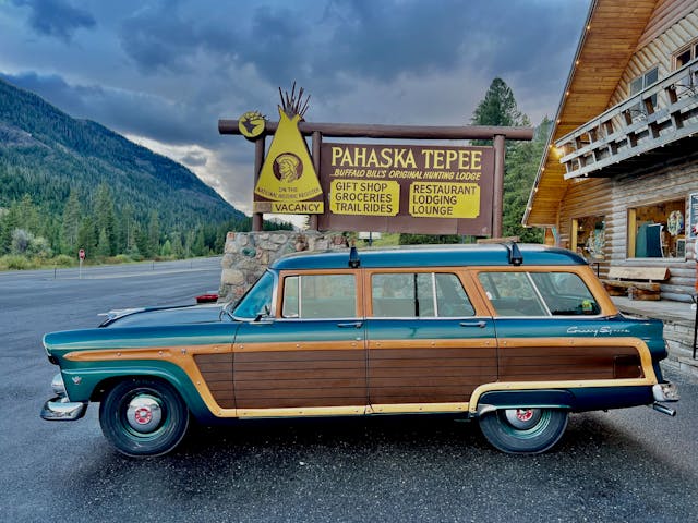 Never Stop Driving Ford Country Squire side profile parked by Pahaska Teepee sign