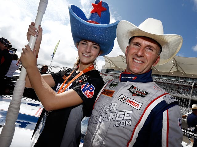 Ben Keating stand next to a grid girl in a cowboy hat before the Lone Star Le Mans
