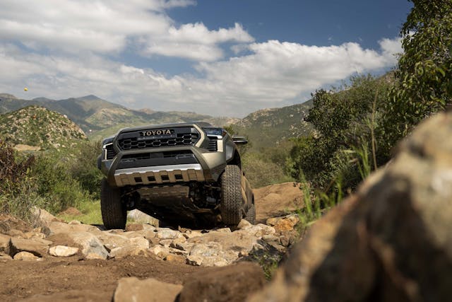2024 Toyota Tacoma Trailhunter exterior front end coming over rocks in desert