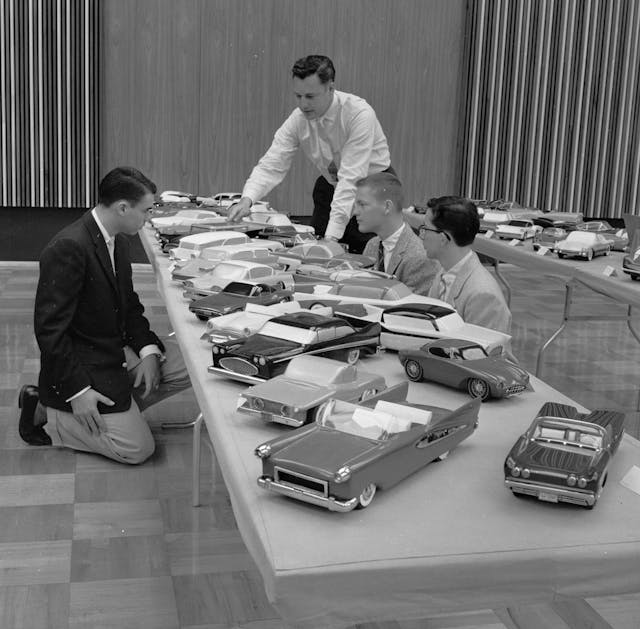 Executives and contestants reviewing a range of scale model cars