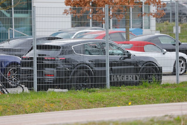 Porsche K1 EV Prototype SUV Spy Shot rear three quarter through fence