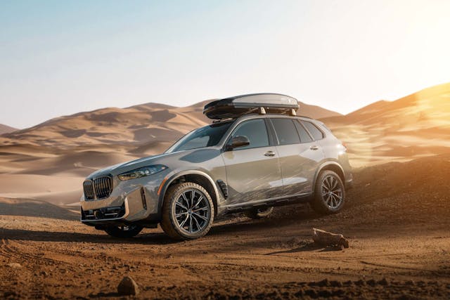 2025 BMW X5 Silver Anniversary Edition exterior side profile with roof box in desert