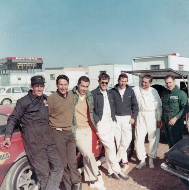 (L-R): Bill Scott, Gib Hufstader, Roger Penske, George Wintersteen, Dick Guldstrand, Ben Moore and Bill "Murph" Mayberry with Penske's Traco-built 427-powered 1966 Corvette